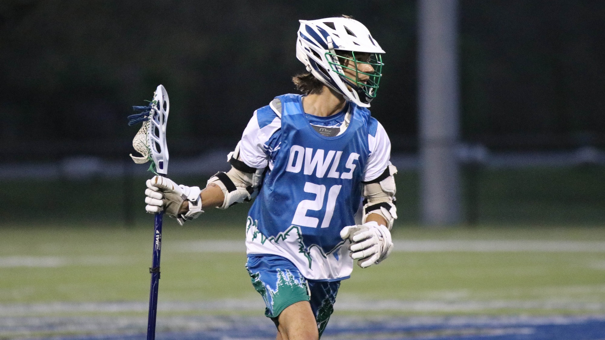 Men's Lacrosse player, Timmy Carcel stops to look at the field with the ball in his stick.