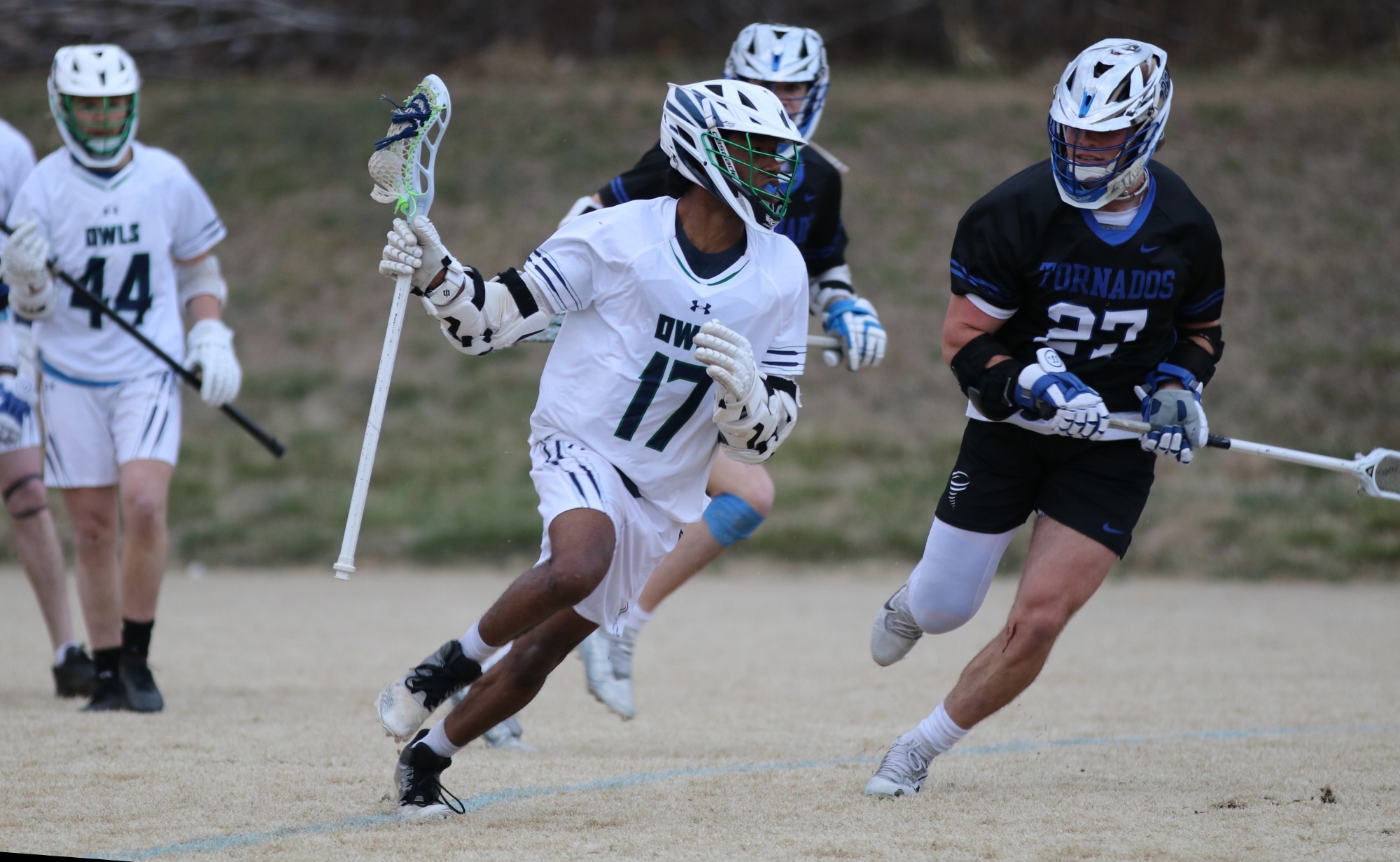 Warren Wilson lacrosse player, Jayshawn Bruce runs along side his opponents with the ball.