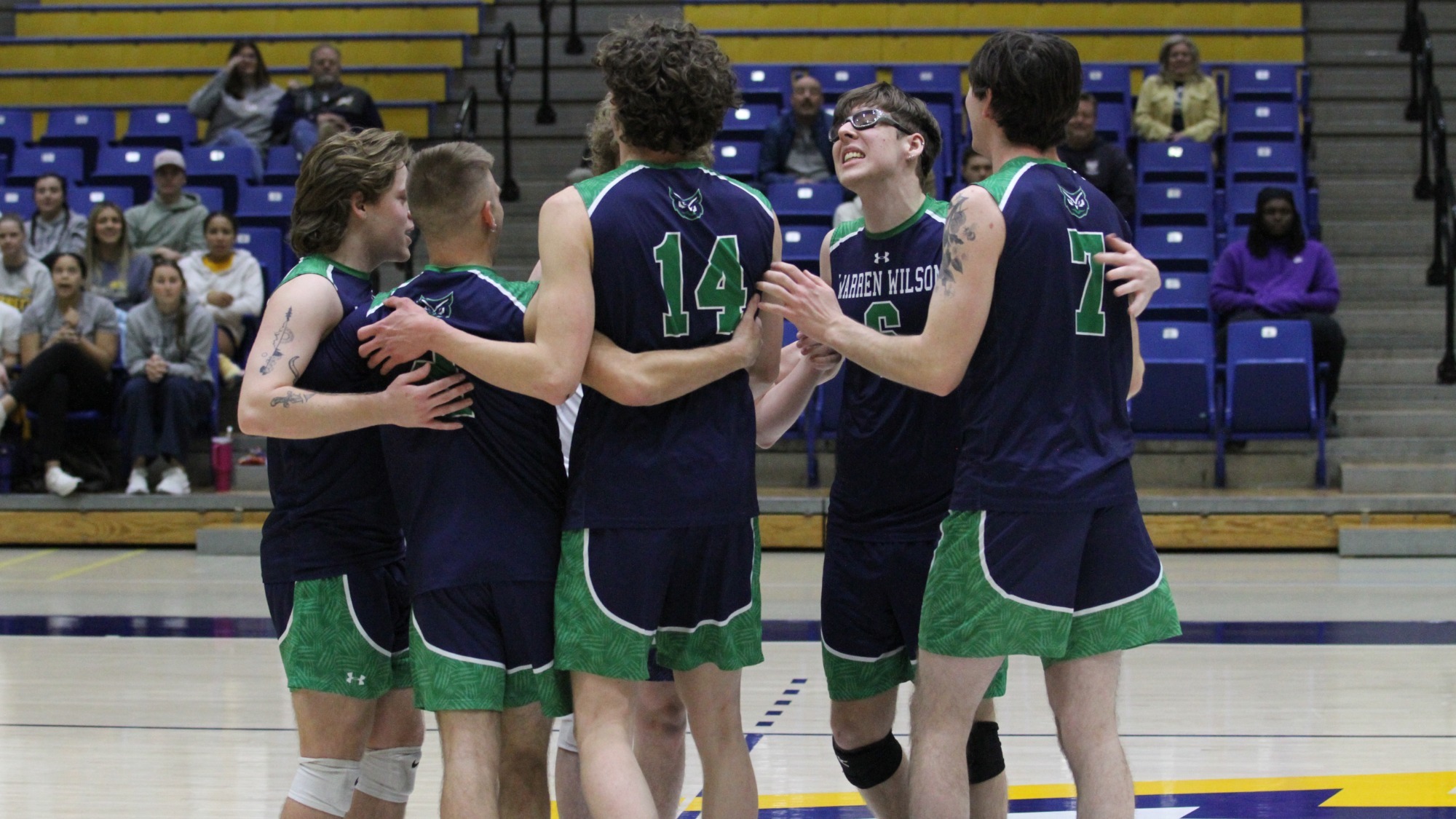 Th2 2024-25 men's volleyball team huddles together after scoring a point.