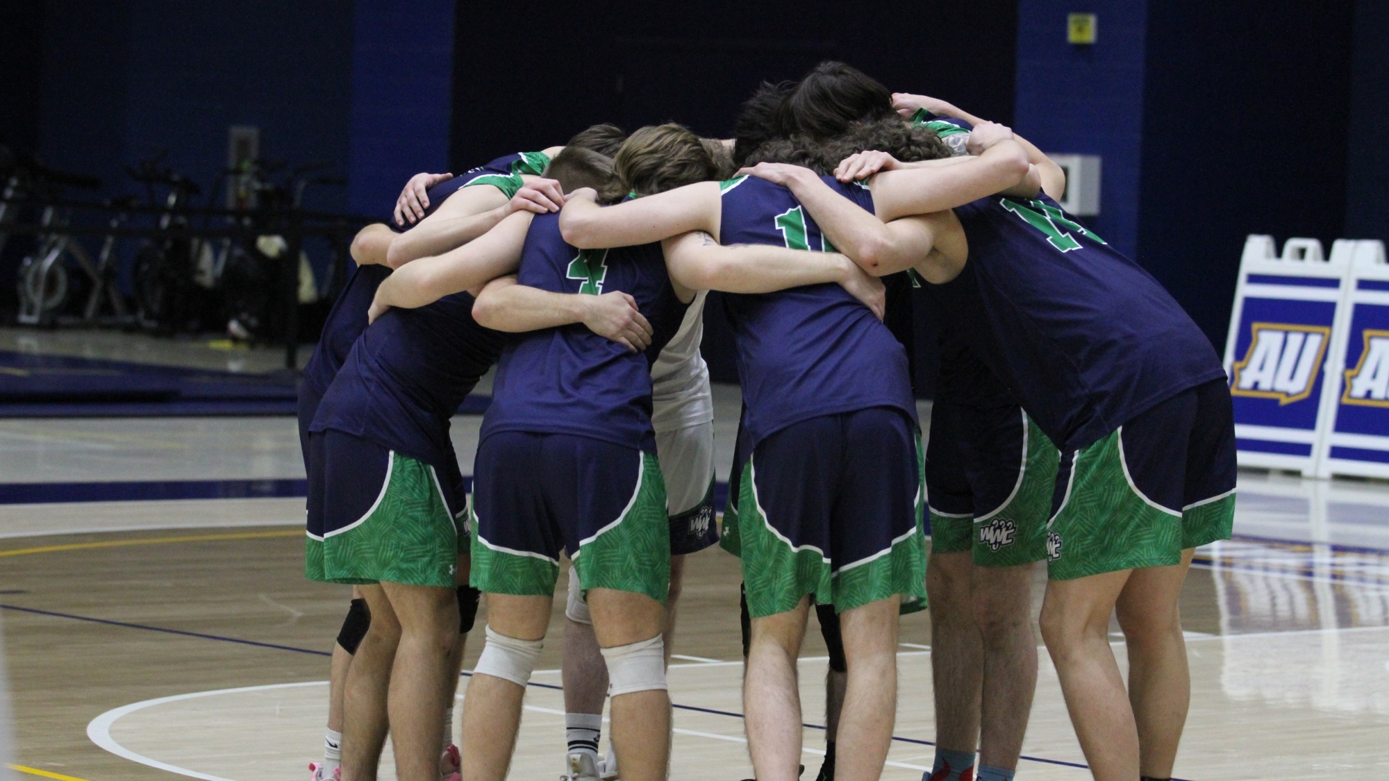Men's Volleyball team huddles together during a break in the game.