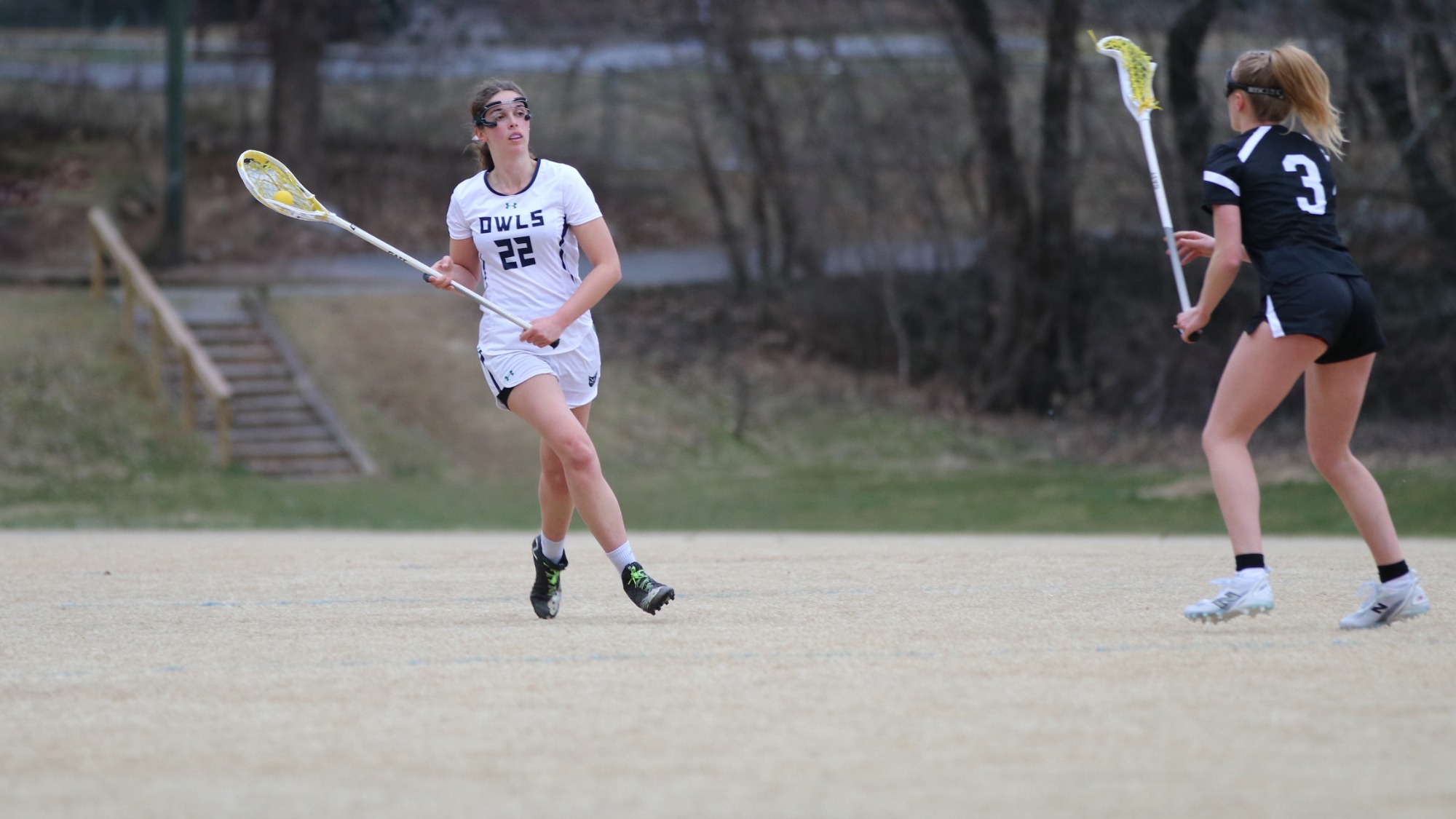 Women's Lacrosse player, Taylor Smith takes the ball towards her defender and down the field.