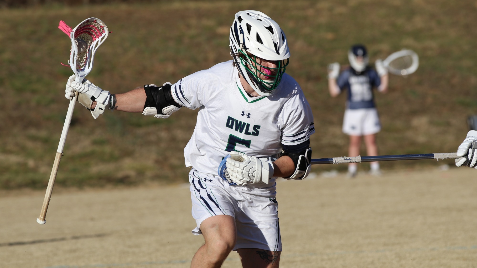 Men's lacrosse player, Jude Searles, keeps the ball away from his opponent.