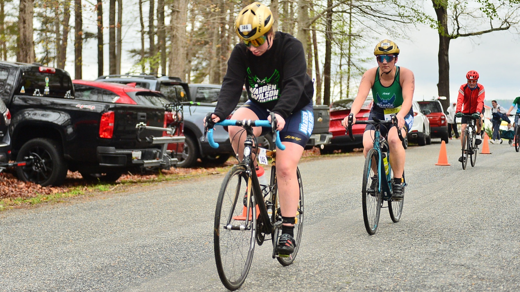 Two members of the women's triathlon team at Warren Wilson are on their bikes, peddling down the road at a race.