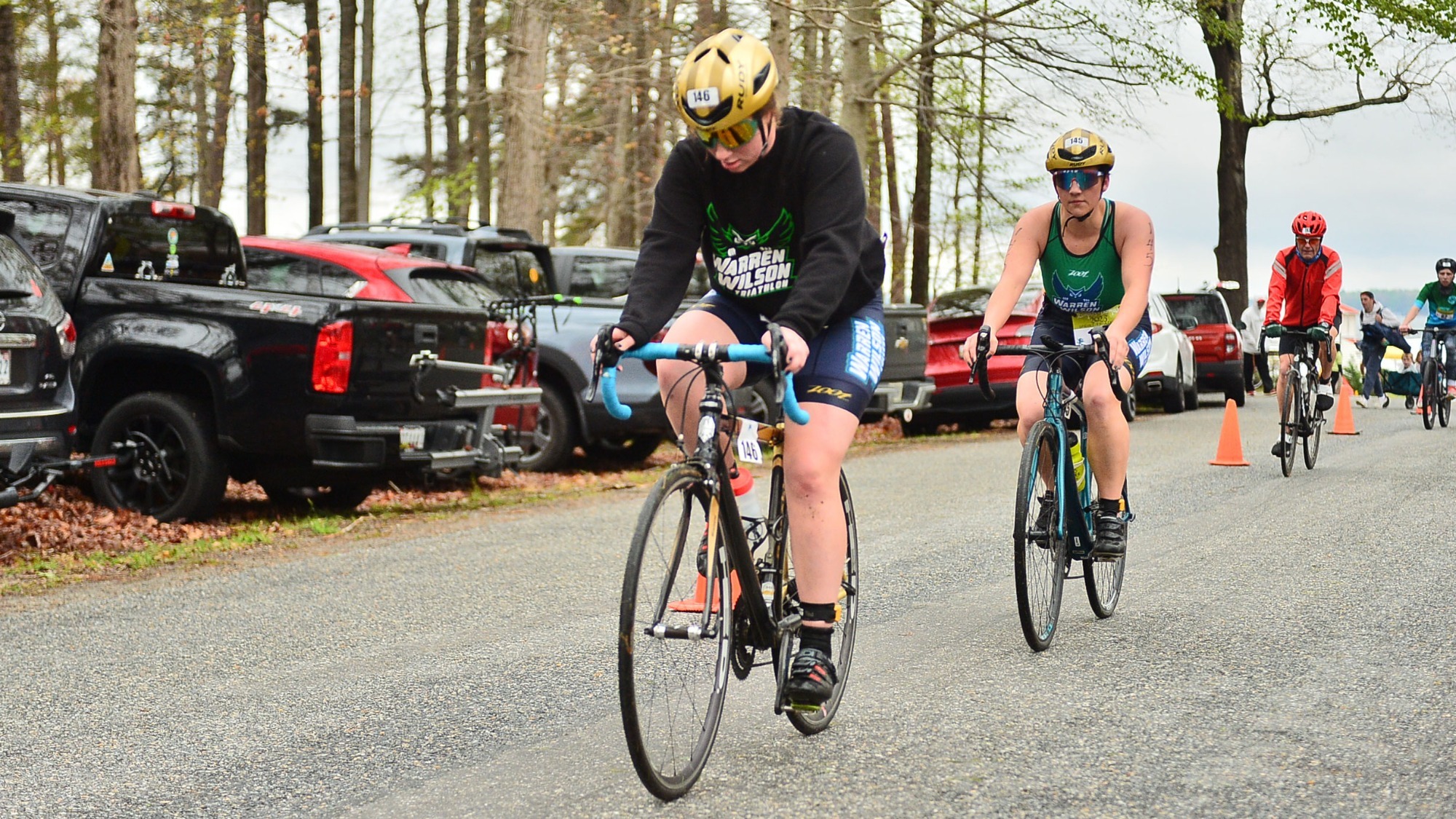 Two Warren Wilson Triathlon athletes ride their bike down the road in competition